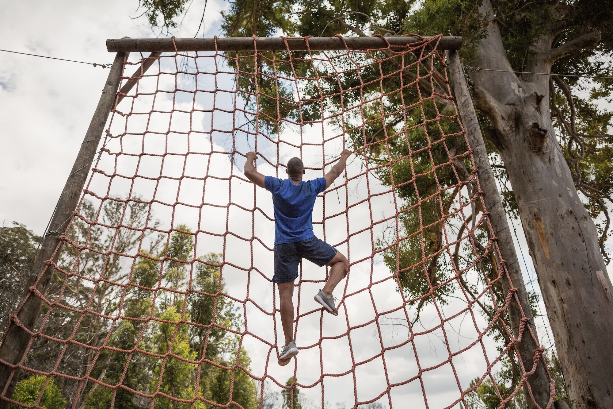 Fit man climbing a net during obstacle course