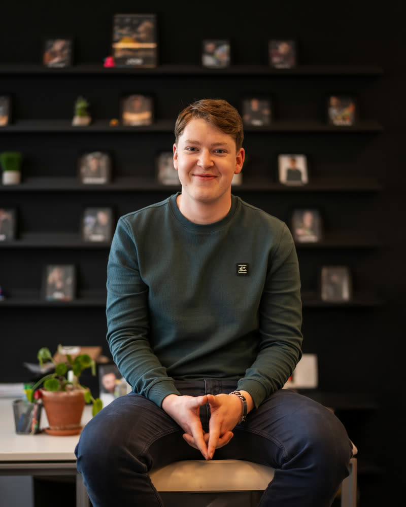 Kevin Helgers, zittend op een bureau in de studio