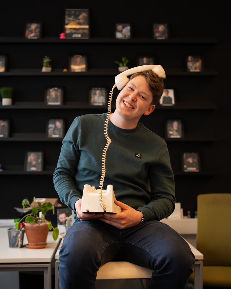 Kevin Helgers lachend met de hoorn van een oude telefoon tegen zijn oor